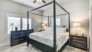 A four-poster bed with a dark frame, a bedside table with a lamp, and a dresser with drawers. - ~ 1 Mi to Pier & Beaches! Family Home in Galveston (Galveston)
