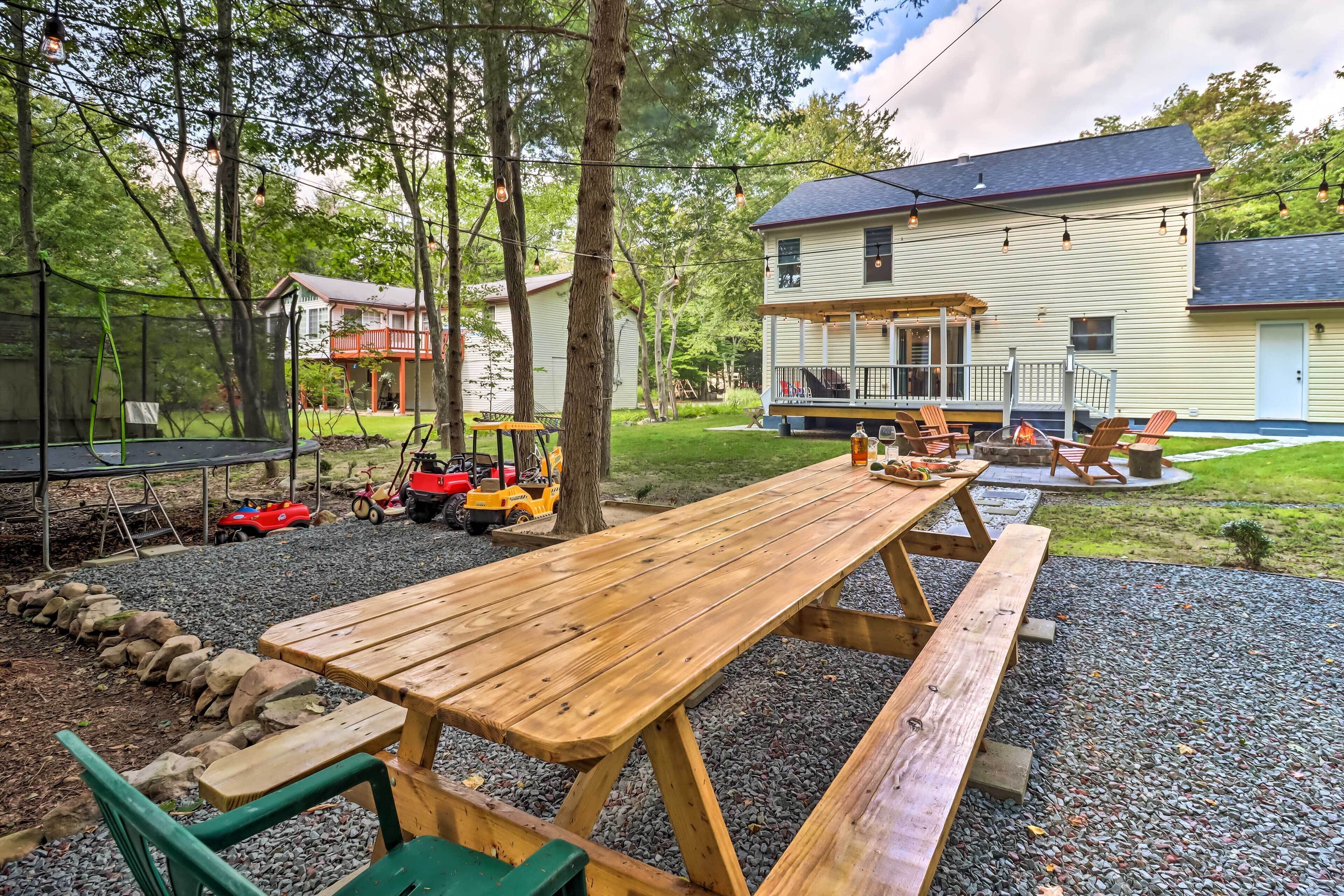 A picnic table with benches, surrounded by a gravel area and a grassy lawn.