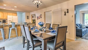 A dining area with a wooden table set for four, surrounded by upholstered chairs.