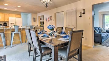 A dining area with a wooden table set for four, surrounded by upholstered chairs.