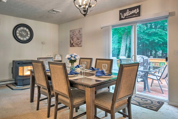 A dining area with a wooden table, chairs, a clock, and a fireplace.