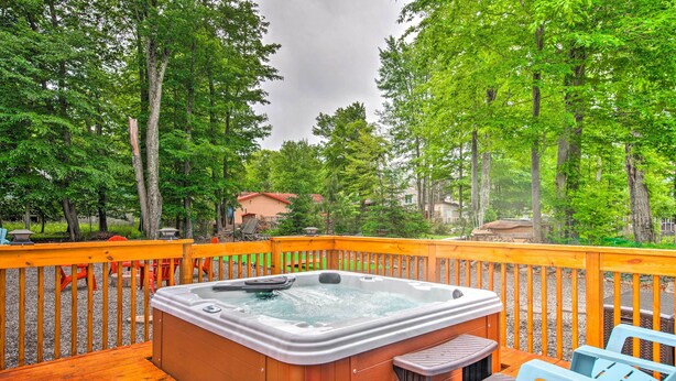 A hot tub on a wooden deck surrounded by trees, with a view of houses in the background.