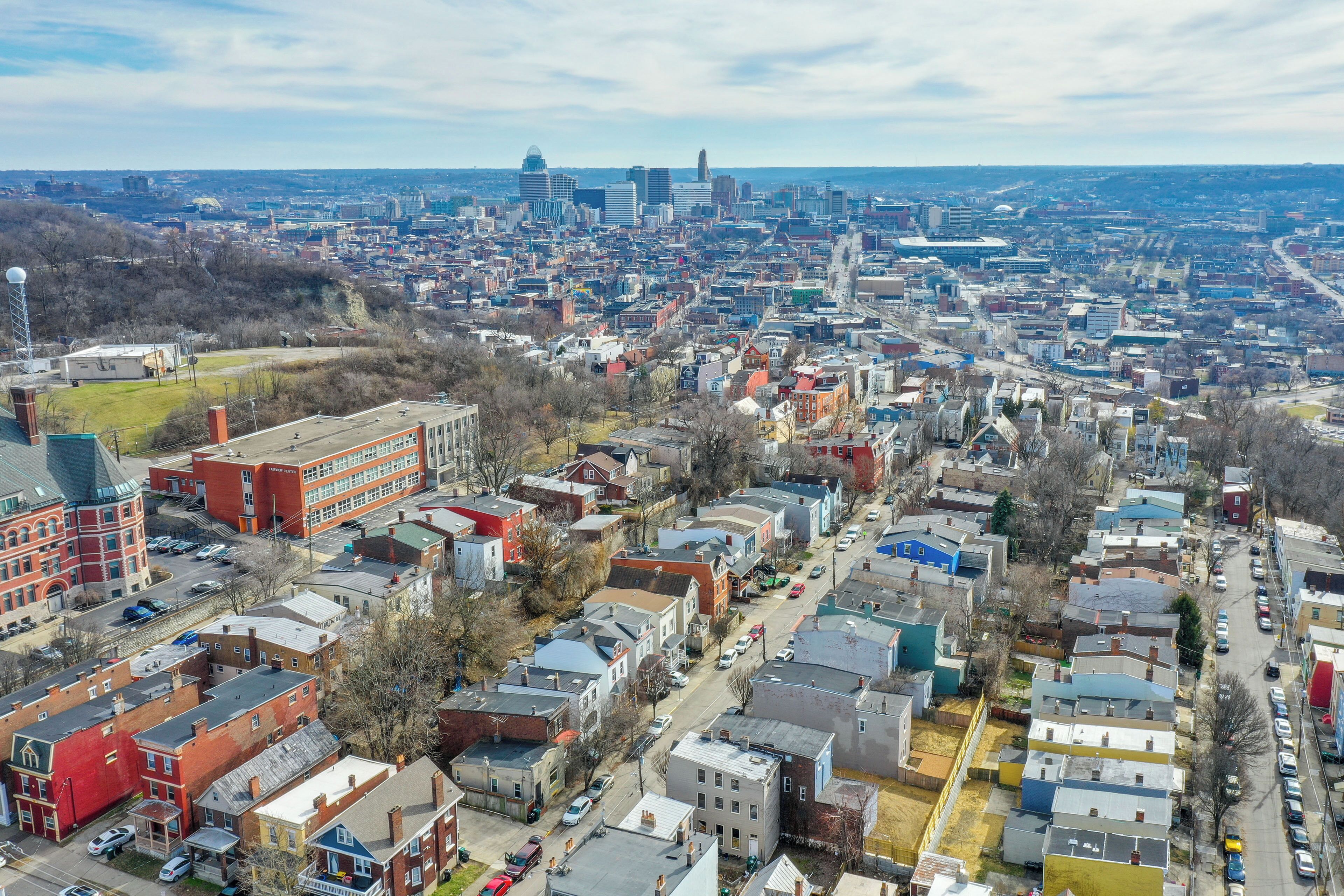 A cityscape with a mix of residential and commercial buildings, a prominent red building, and a distant skyline with high-rise buildings.