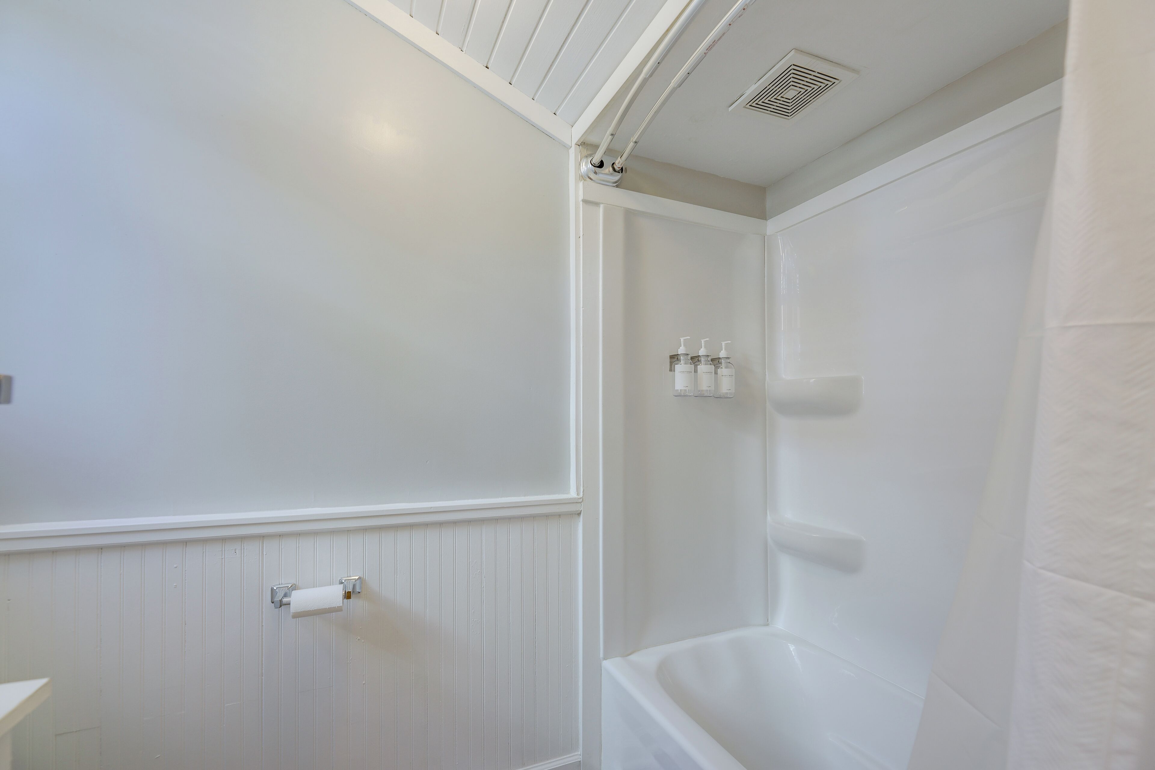 A bathroom with a white bathtub, a toilet, and a shower area.