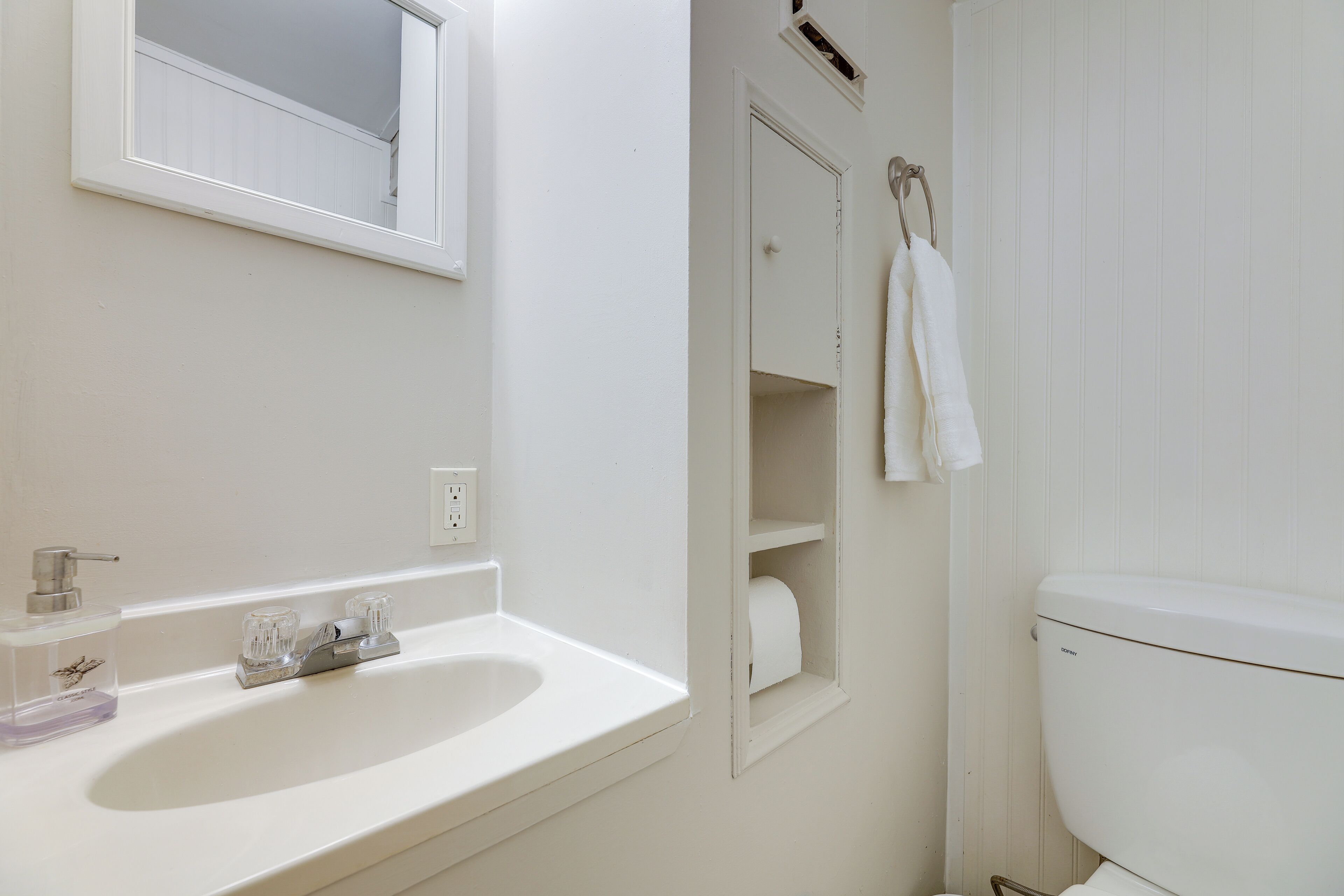 Un baño con un lavamanos blanco, un espejo, un inodoro y una toalla colgada en la pared.