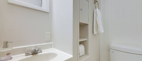 Un baño con un lavamanos blanco, un espejo, un inodoro y una toalla colgada en la pared.