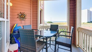 Un espace extérieur abrité, équipé d’une table et de chaises, agrémenté d’une décoration sur le thème du soleil et offrant une vue sur la plage.