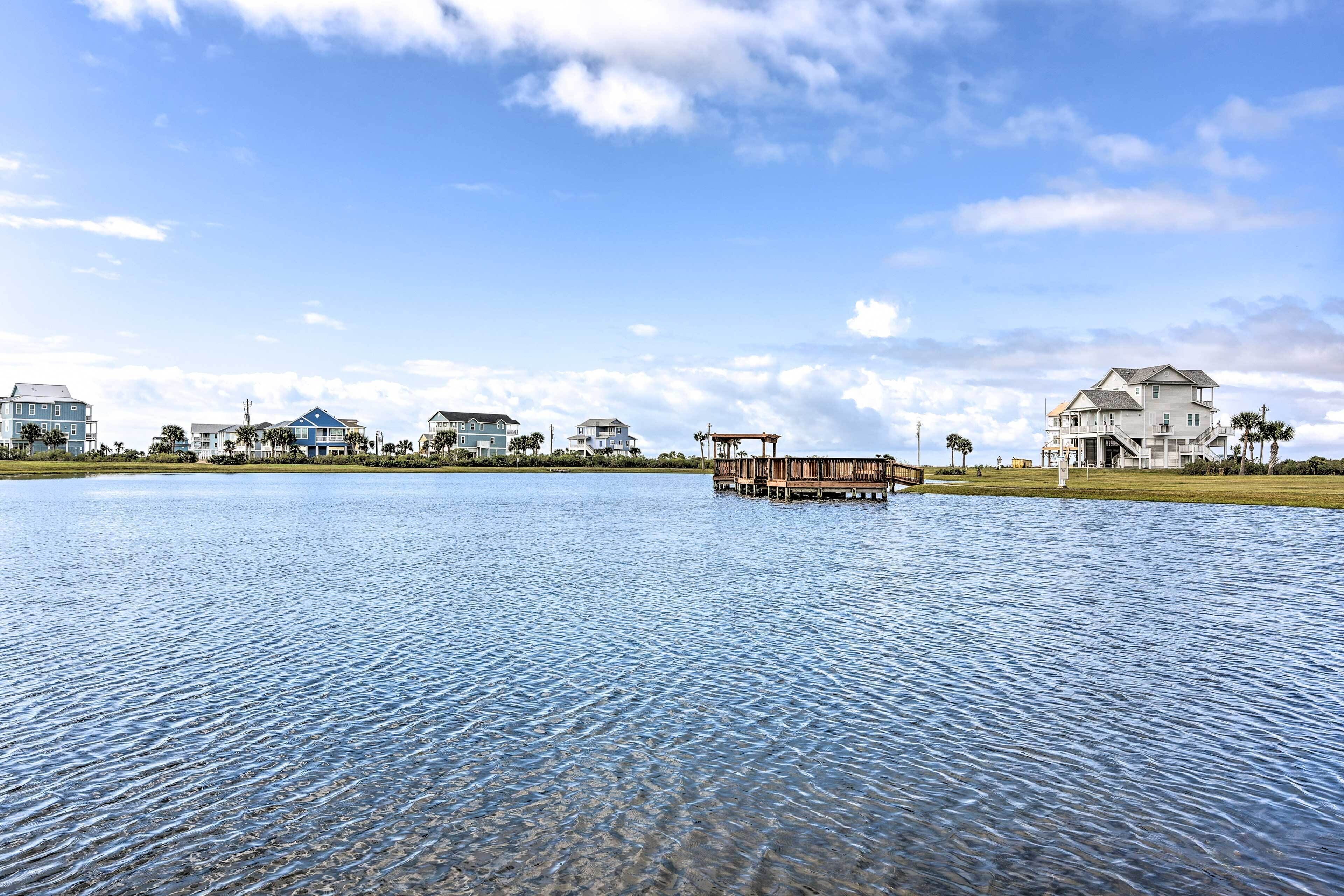 A waterfront property with a dock, houses, and a clear sky.