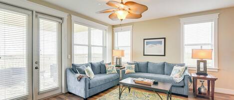 A living room with a ceiling fan, two sofas, a coffee table, and a patterned rug.