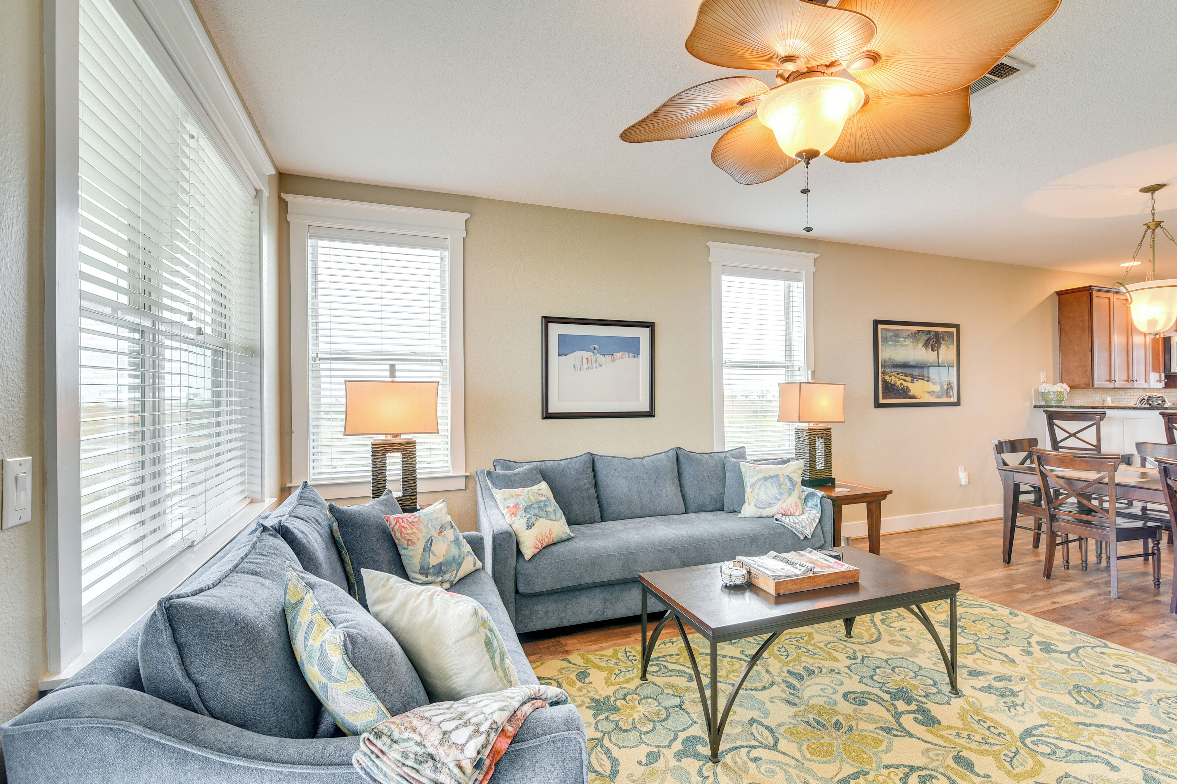 A living room with a sofa, coffee table, and lamps. There is a dining area with a table and chairs.