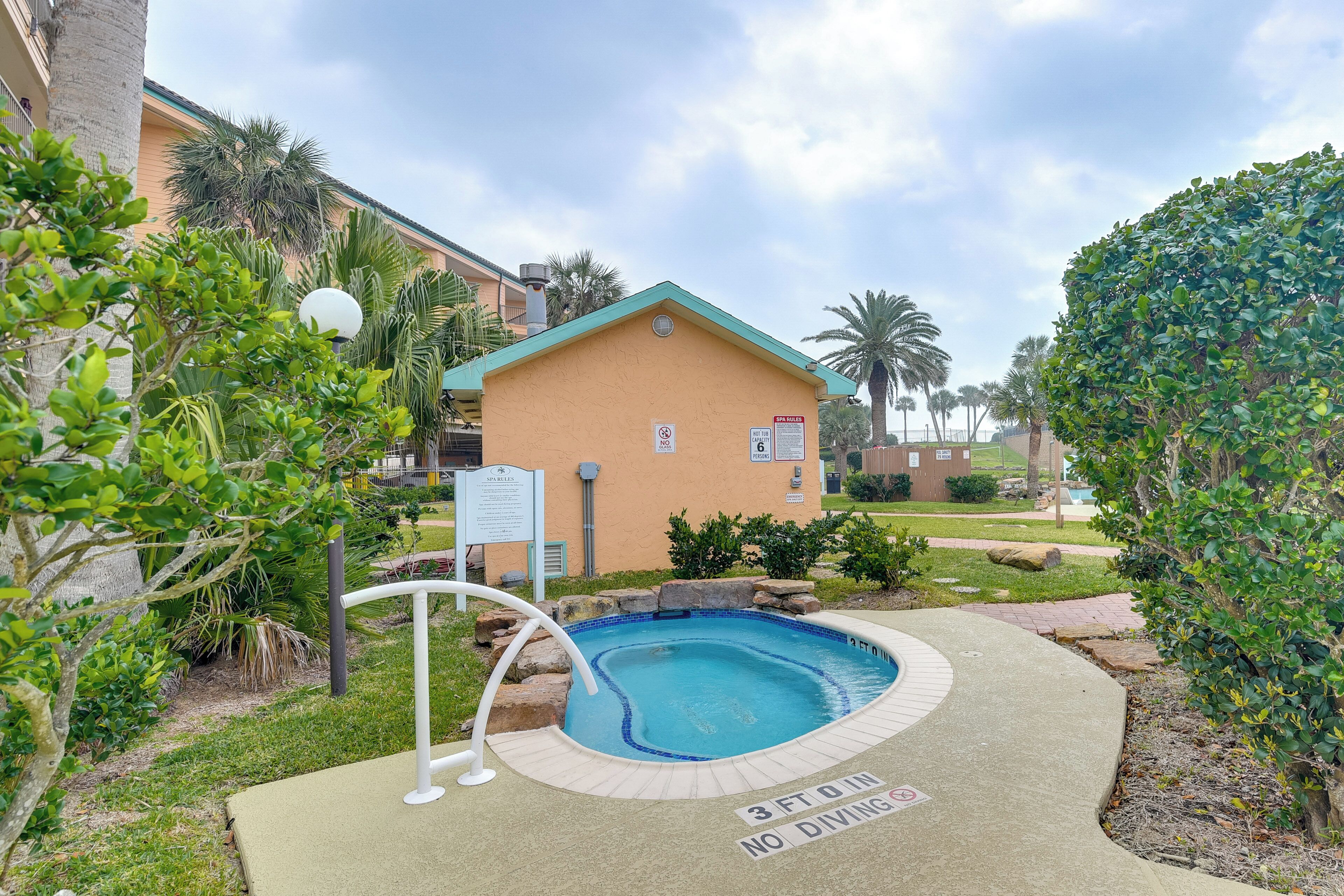 A small, single-story building with a pool area, surrounded by greenery and palm trees.