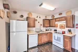A kitchen with wooden cabinets, a white refrigerator, a dishwasher, a stove, and various kitchen appliances.