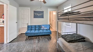 Ein Zimmer mit einem blauen Sofa, einem Deckenventilator, Etagenbetten und einer Tür zu einem weiteren Raum.
