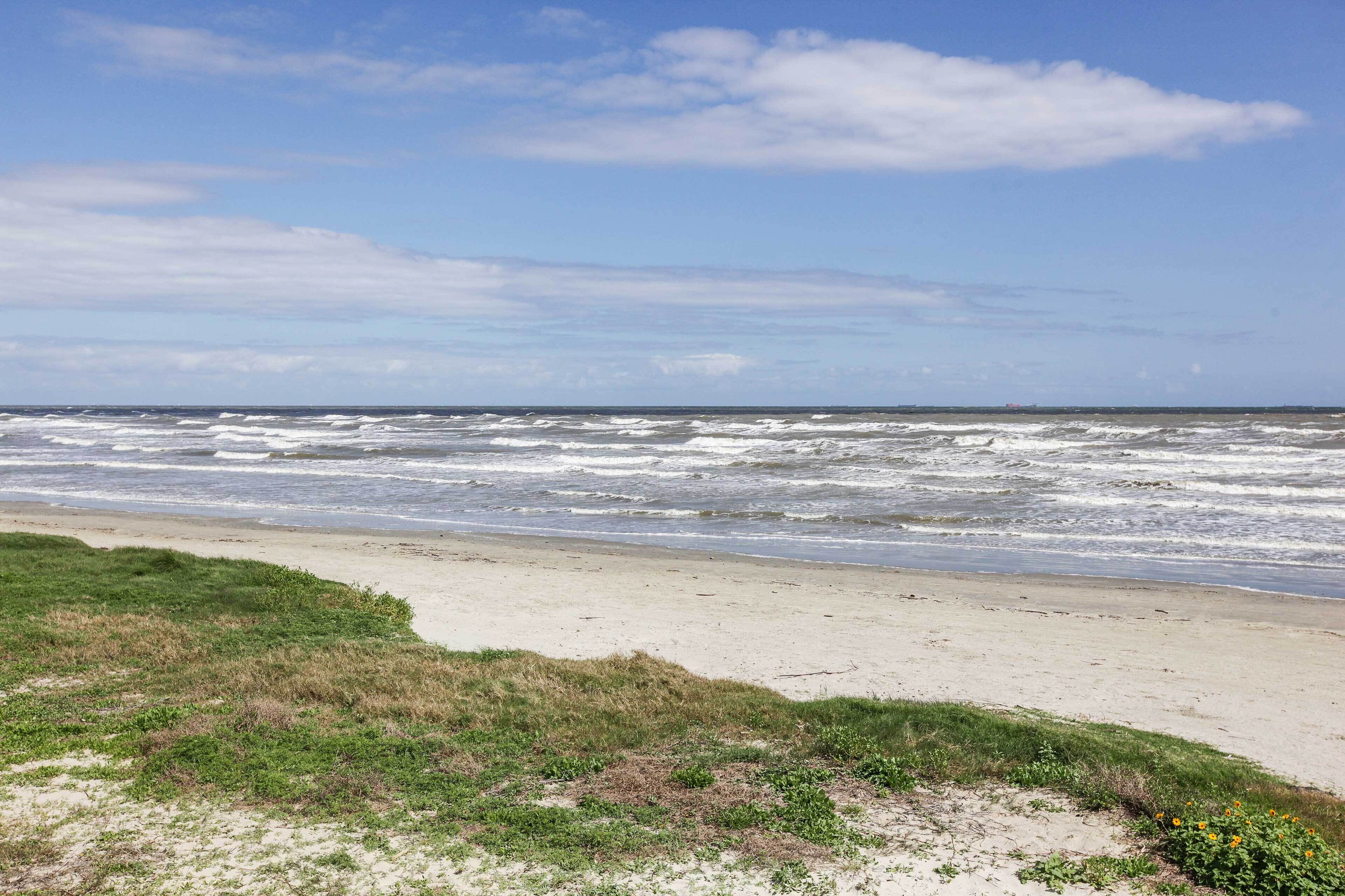 A beach with waves and a clear sky.