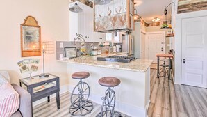 Una cucina con isola centrale, sgabelli da bar, lampade a sospensione e una parete rustica.