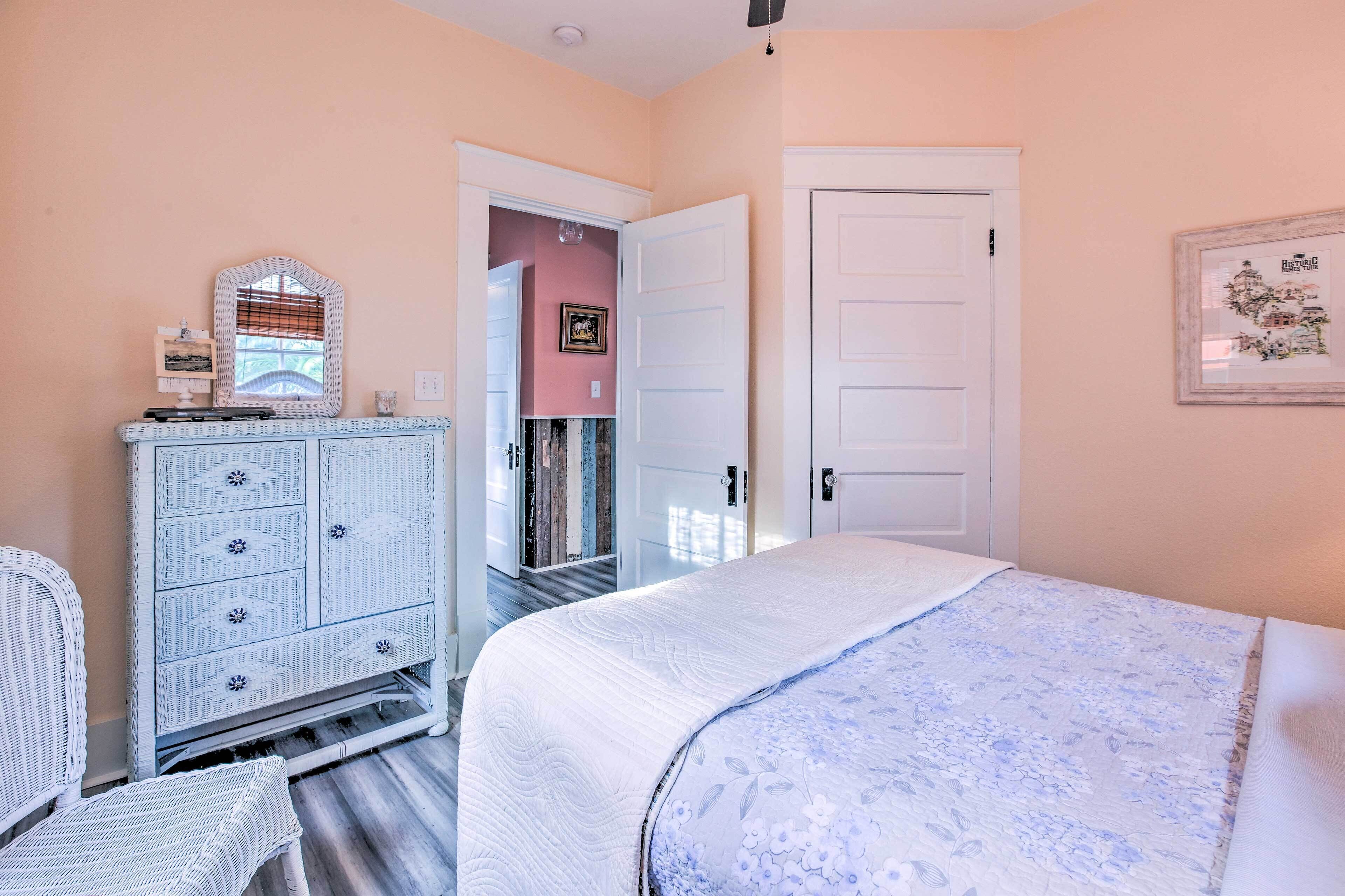 Un dormitorio con cama, cómoda, silla y puerta.