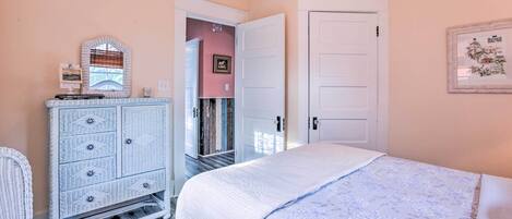 Un dormitorio con cama, cómoda, silla y puerta.