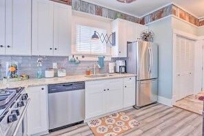 A modern kitchen with white cabinets, a stainless steel refrigerator, a dishwasher, and a stove. - Walk to Pleasure Pier! 'rose's Beach House' (Galveston)