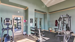 Ett gym med träningsredskap, en spegel och en dörr som leder ut.