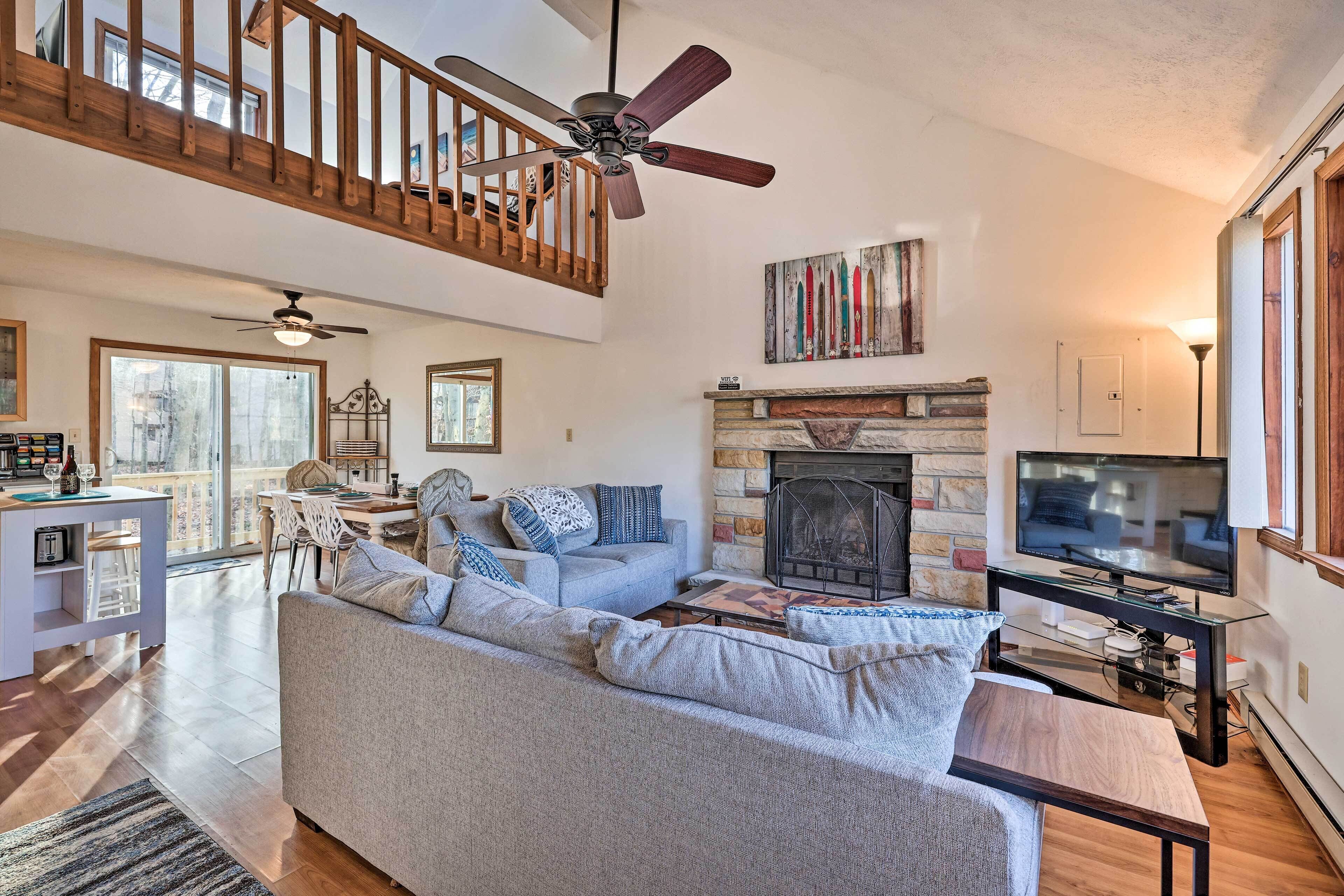 A spacious living room with a high ceiling, a fireplace, a television, and a dining area.