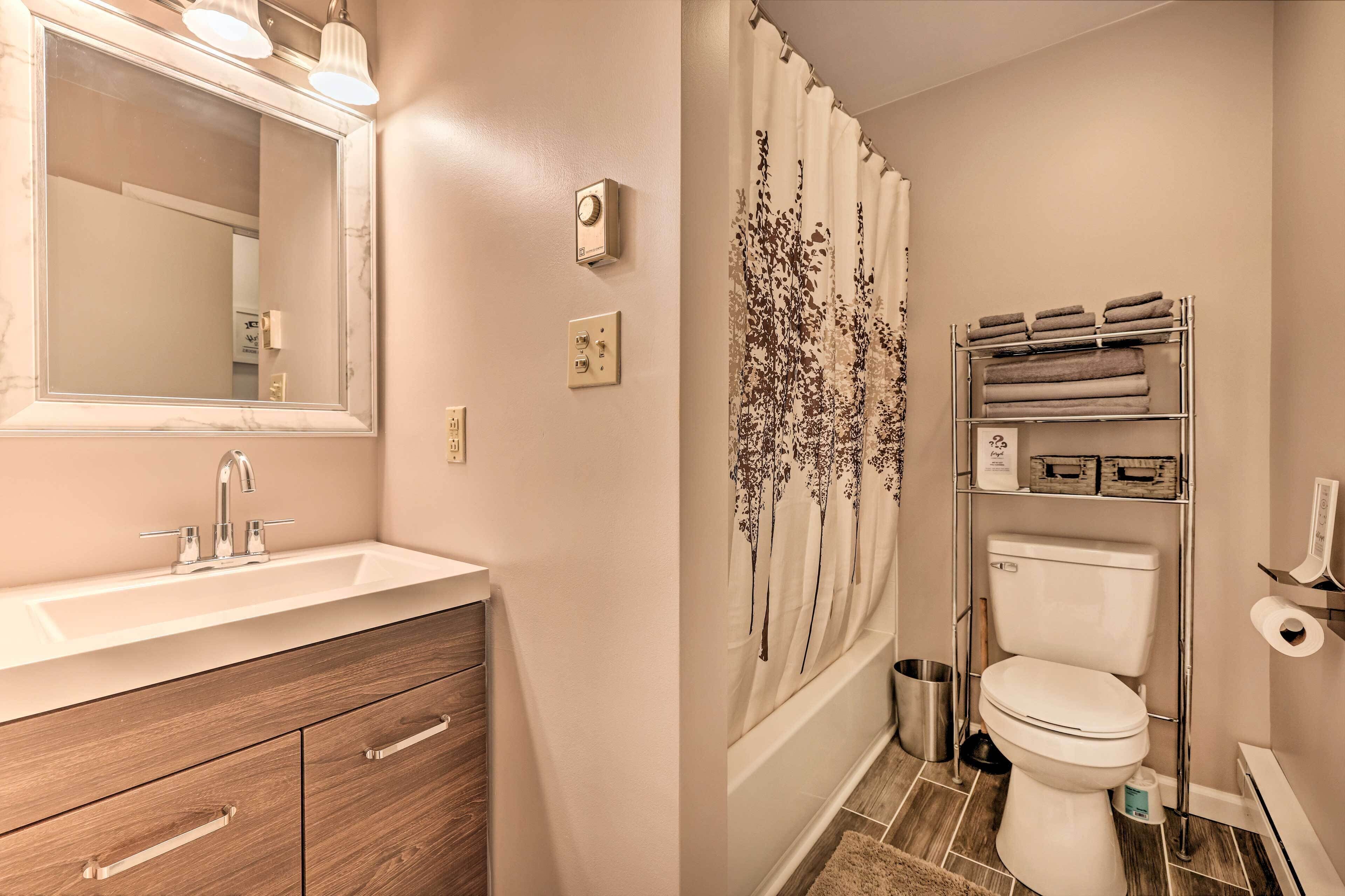 Ein Badezimmer mit Waschbecken, Spiegel, Handtuchhalter, Toilette und Duschvorhang.