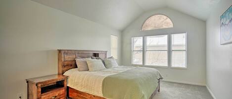 A bedroom with a wooden bed, a nightstand, and a window with blinds.