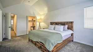 Une chambre avec un lit en bois, une couverture verte et du linge de lit blanc. On y trouve une armoire avec un miroir et une lampe sur une table de chevet.