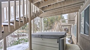 Un espace extérieur abrité, avec un grand objet rectangulaire de couleur grise, qui pourrait être une piscine ou un jacuzzi, situé sous une pergola en bois.