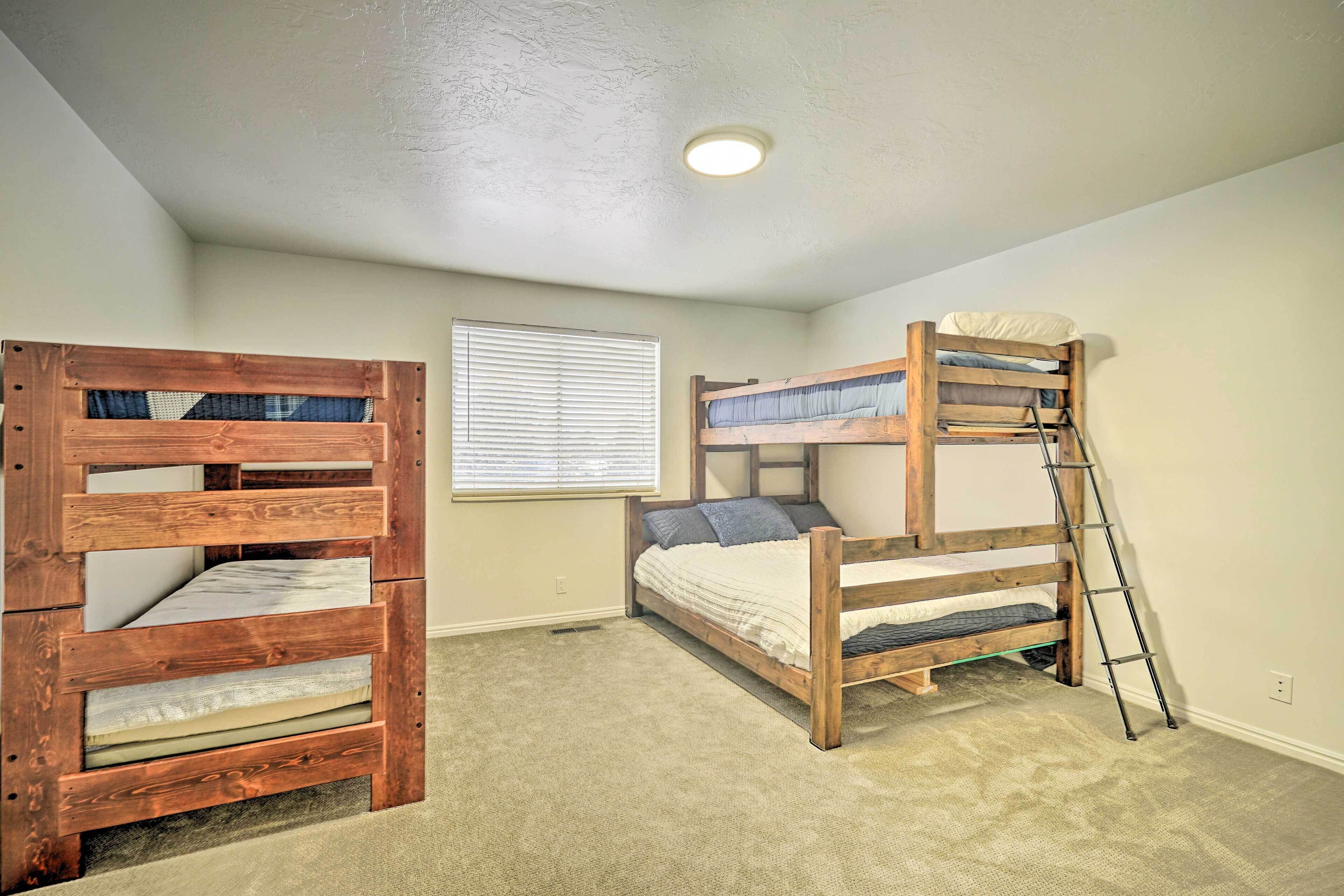 A room with two bunk beds, a window with blinds, and a ceiling light.