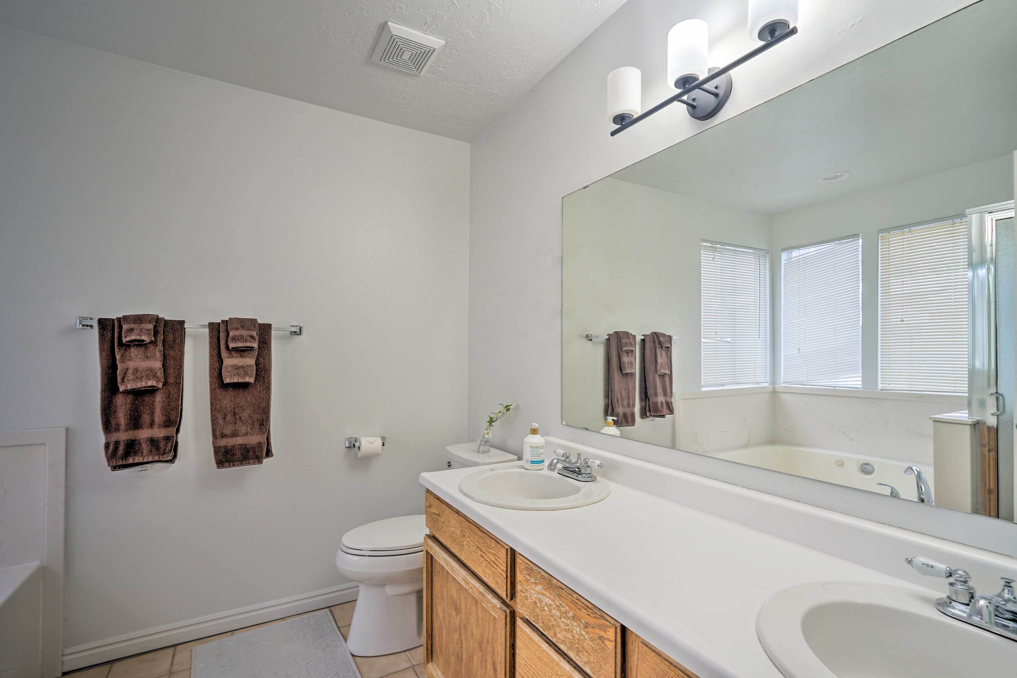 Une salle de bain avec un lavabo blanc, un miroir et deux serviettes accrochées au mur.
