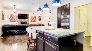 A modern kitchen with a central island, dark cabinetry, and a built-in oven. - Downtown DC Home w/ Furnished Patio! (Washington)