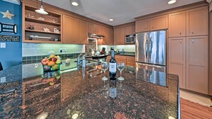 A modern kitchen with granite countertops, stainless steel appliances, and wooden cabinets. - Steps to Pirate Beach: Galveston Home w/ Deck! (Galveston)