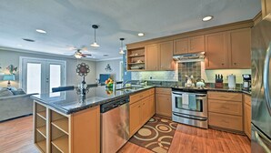 A modern kitchen with wooden cabinets, stainless steel appliances, and a central island. - Steps to Pirate Beach: Galveston Home w/ Deck! (Galveston)