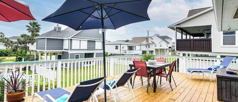 A wooden deck with outdoor furniture, including chairs and a table, and a large umbrella providing shade.