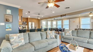 A spacious living room with two grey sofas, a white coffee table, and a ceiling fan. - Steps to Pirate Beach: Galveston Home w/ Deck! (Galveston)