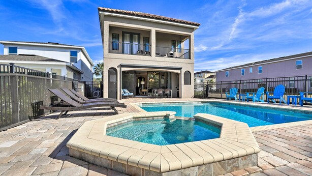 A two-story house with a swimming pool, lounge chairs, and a fenced patio area. - Luxe Reunion House w/ Private Pool: Near Disney! (Kissimmee)