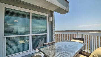 Un balcon avec une table et des chaises en verre, une balustrade blanche et une vue sur le paysage.