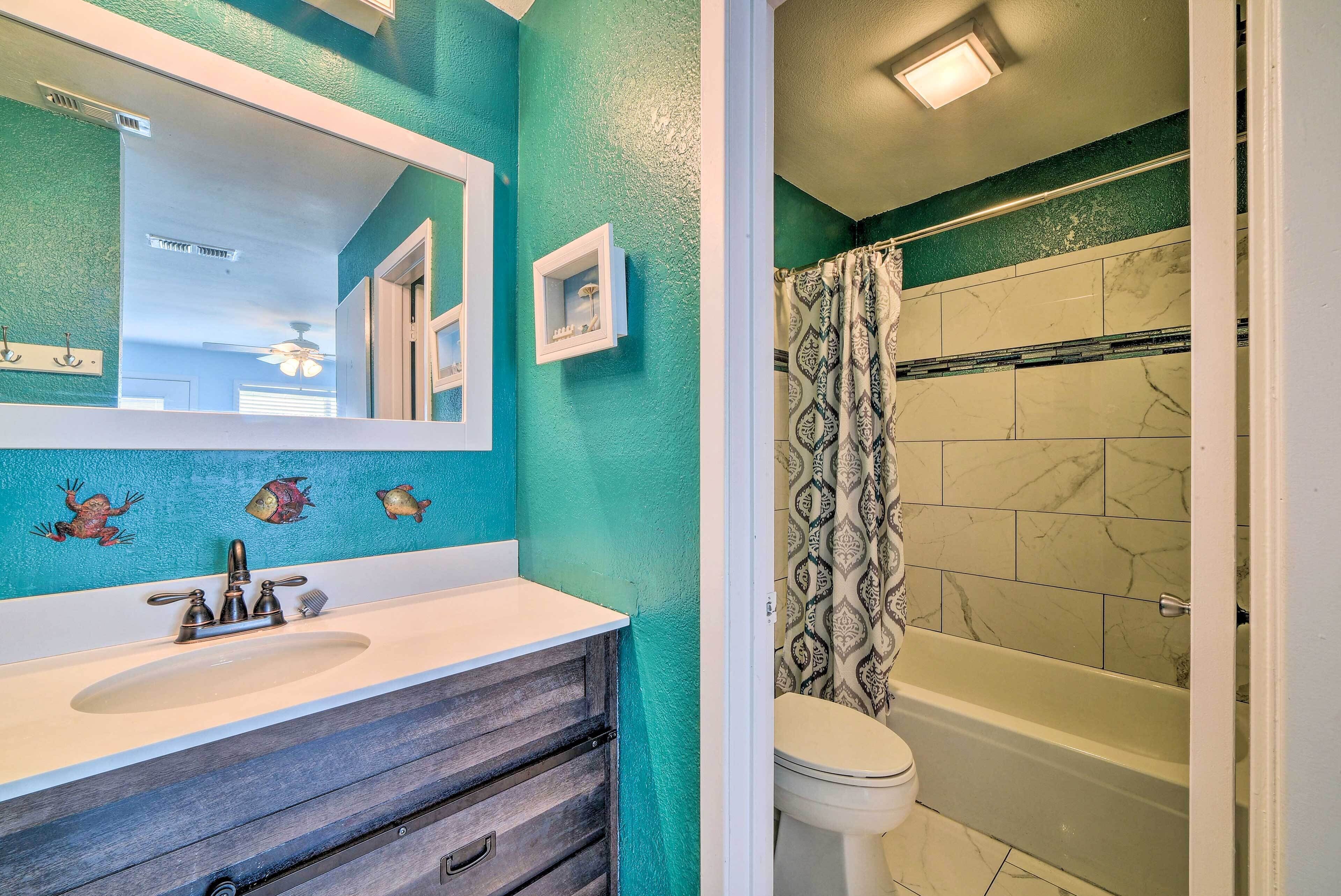A bathroom with a white sink, a large mirror, and a shower with patterned curtains.