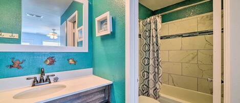A bathroom with a white sink, a large mirror, and a shower with patterned curtains.