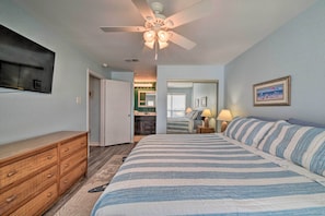 Ein Schlafzimmer mit Bett, Kommode, Deckenventilator und Fernseher an der Wand.