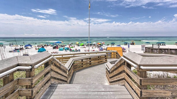 A wooden boardwalk leading to a beach with umbrellas and people. - Destin Condo w/ Pool Access < 1 Mi to the Beach! (Destin)