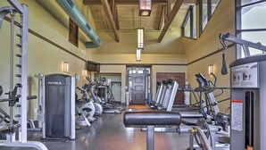 Un gimnasio con diverso equipo de ejercicio, que incluye cintas de correr, máquinas de pesas y una prensa de banca.