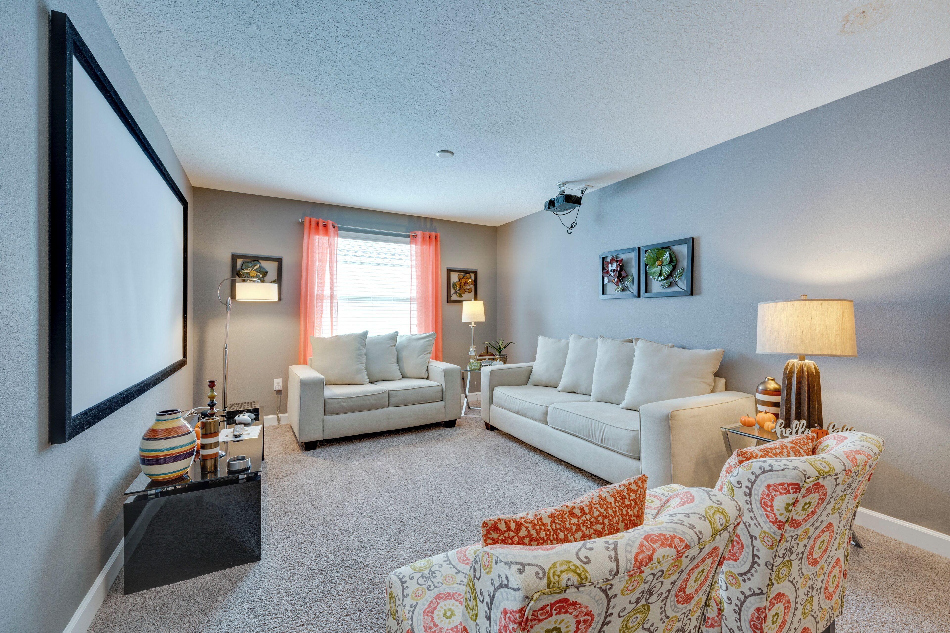 A living room with two sofas, a patterned armchair, a coffee table, and a side table with a lamp.