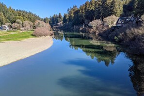 Un hotel con vista a un río tranquilo y colinas cubiertas de bosque.