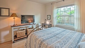 A bedroom with a bed, a desk with a chair, a lamp, and a window with curtains. - Orlando Vacation Rental < 2 Miles to Lake Ivanhoe! (Orlando)