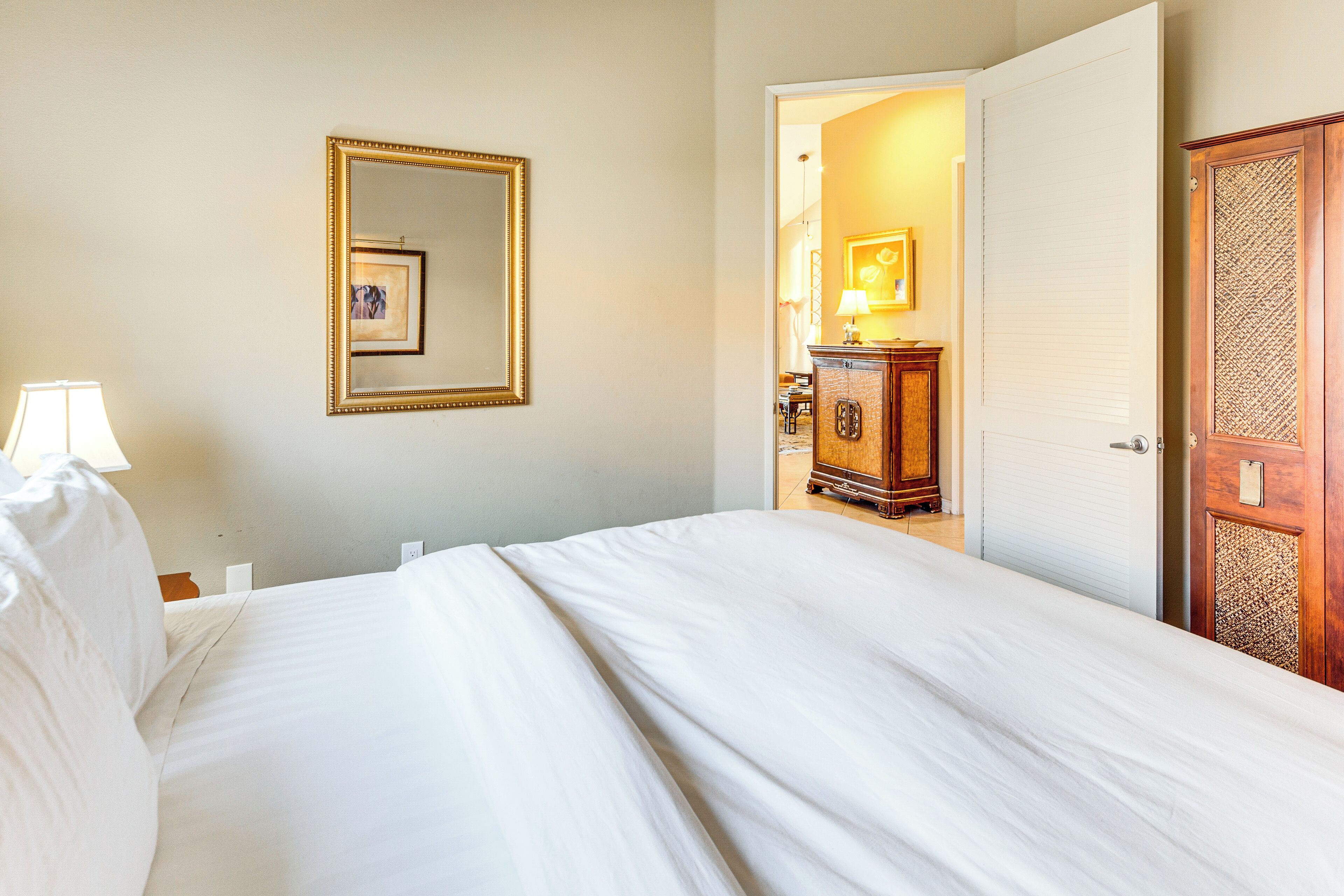 Een hotelkamer met een bed, een spiegel, een dressoir en een deur.