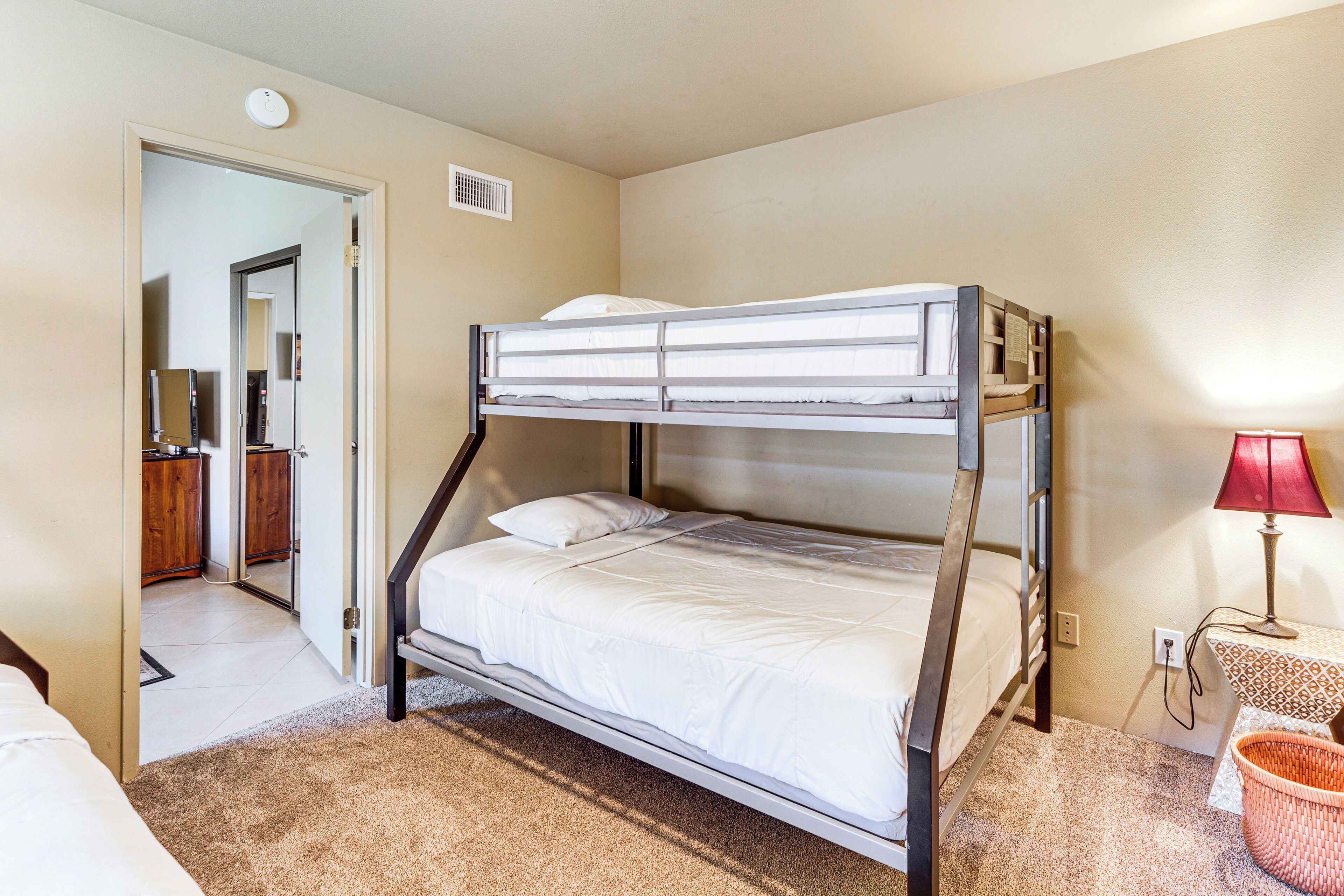 A bunk bed room with a desk and lamp.