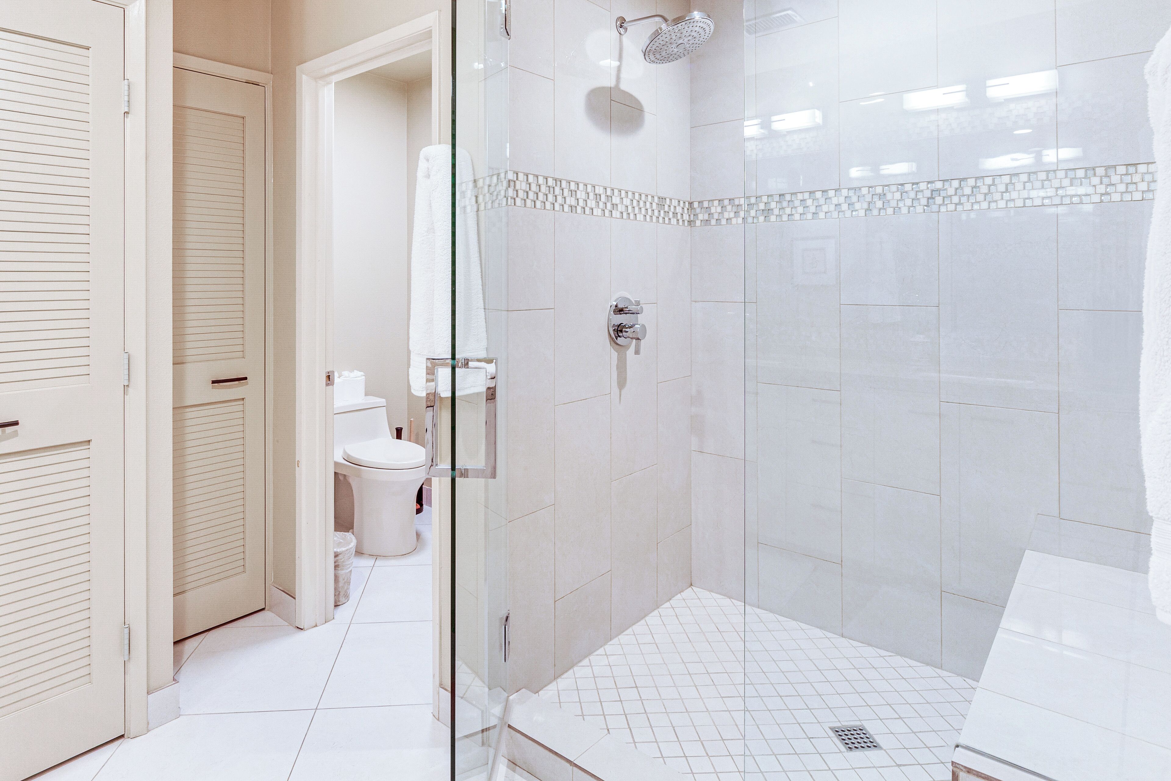 A modern bathroom with a glass-enclosed shower, a toilet, and a sink.