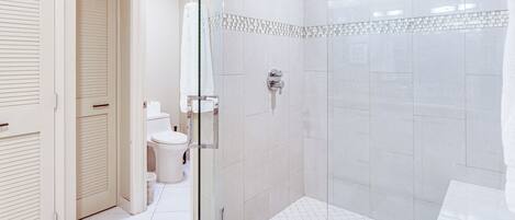 A modern bathroom with a glass-enclosed shower, a toilet, and a sink.