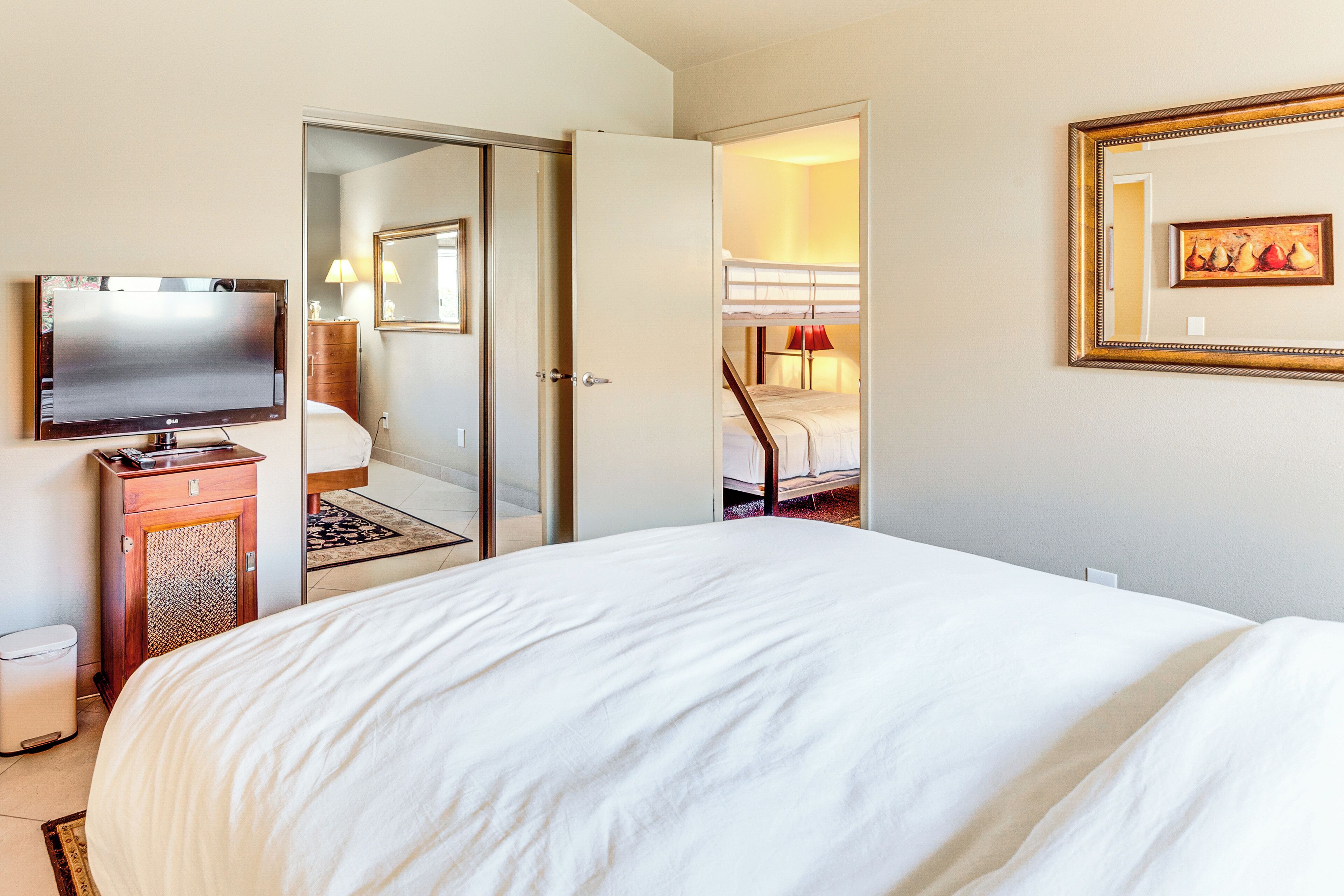 Une chambre d’hôtel avec un grand lit, une télévision, une armoire et un miroir.